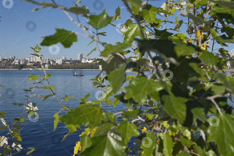Скачать Рыбаки в лодке на водохранилище на фоне города в утренних лучах солнца фотосток Ozero