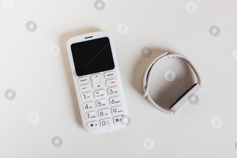 Скачать Крупный план ретро-кнопочного телефона и концепта фитнес-браслета, вид сверху фотосток Ozero