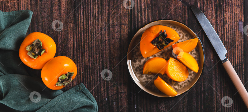 Скачать Кусочки и половинки плодов хурмы на тарелке и на столешнице посмотреть веб-баннер фотосток Ozero