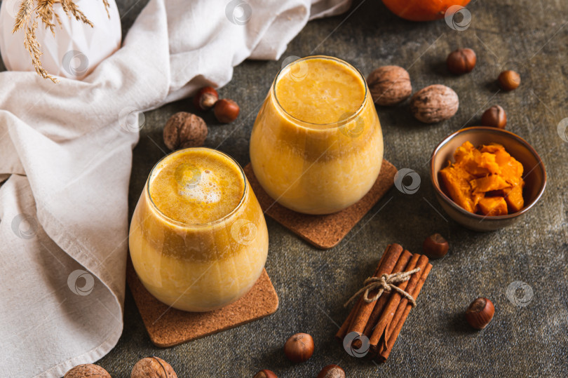 Скачать Осенний латте с тыквенным пюре, орехами и корицей в бокалах на столе фотосток Ozero