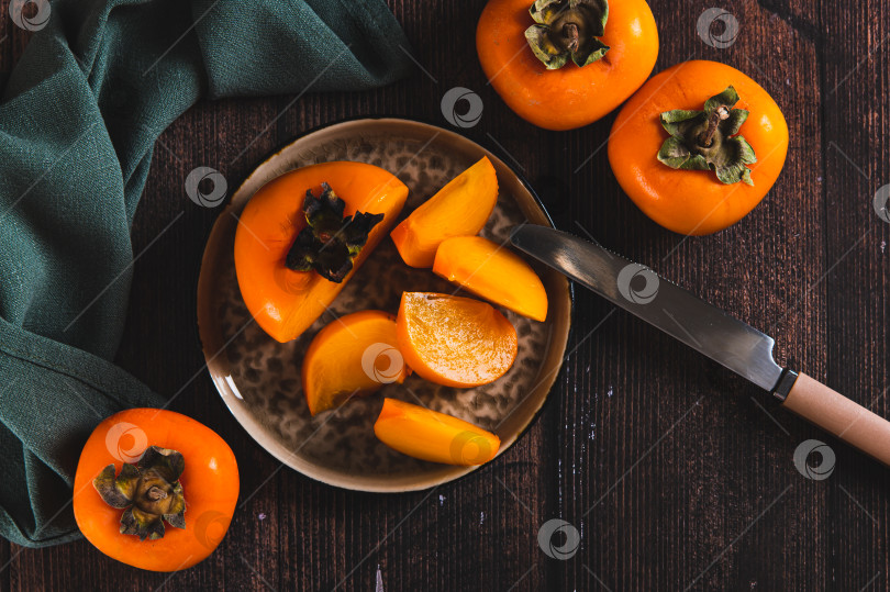 Скачать Свежая спелая нарезанная ломтиками хурма на тарелке на столе вид сверху фотосток Ozero