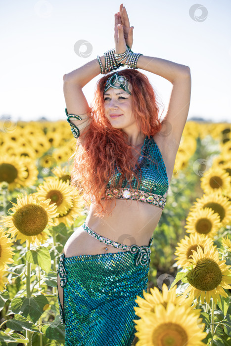Скачать Рыжеволосая восточная танцовщица позирует на поле подсолнухов. фотосток Ozero