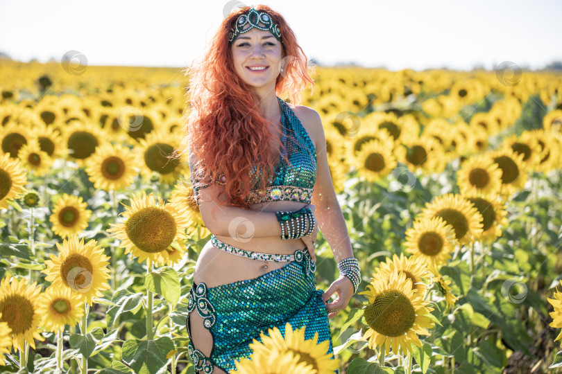Скачать Рыжеволосая восточная танцовщица позирует на поле подсолнухов. фотосток Ozero