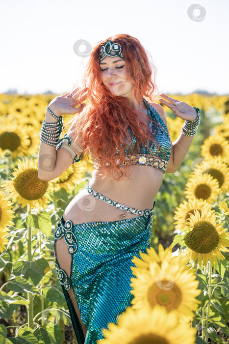 Скачать Рыжеволосая восточная танцовщица позирует на поле подсолнухов. фотосток Ozero