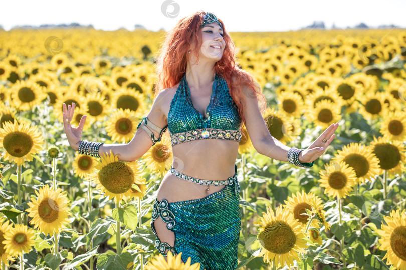 Скачать Рыжеволосая восточная танцовщица позирует на поле подсолнухов. фотосток Ozero
