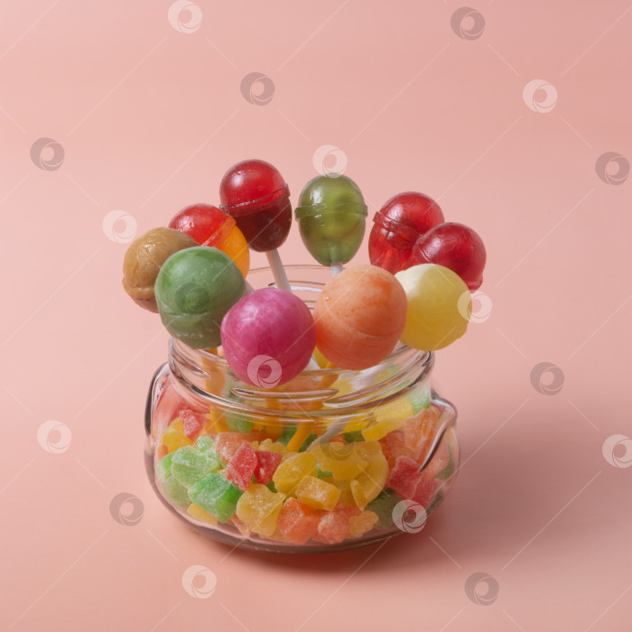 Скачать Круглая баночка с разноцветными леденцами на розовом фоне фотосток Ozero