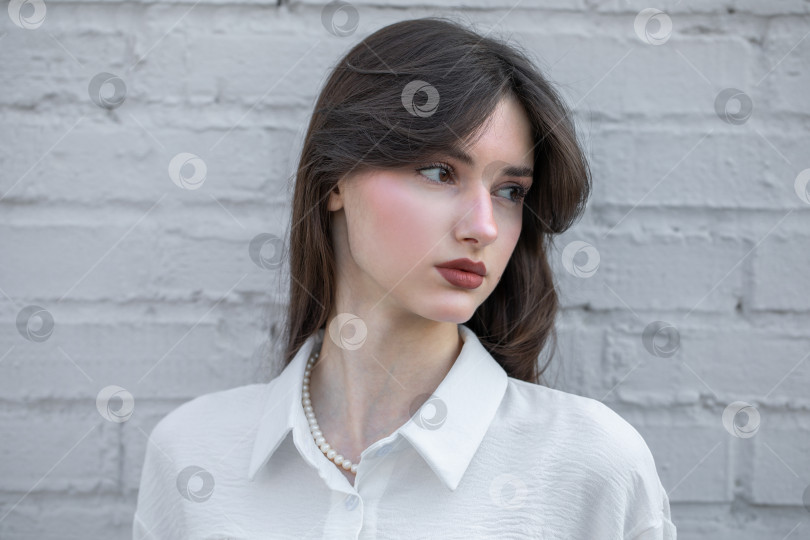 Скачать Портрет молодой красивой брюнетки крупным планом в белой блузке с воротником-стойкой фотосток Ozero