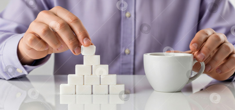 Скачать Мужчина в сиреневой рубашке, укладывающий пирамидку из кубиков сахара рядом с кофейной чашкой, - шаблон баннера о вредном потреблении сахара, риске развития диабета или осведомленности о диете с помощью copyspace. фотосток Ozero