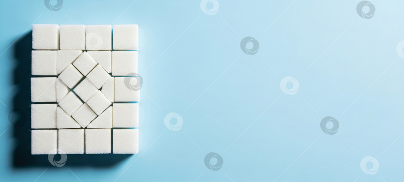 Скачать Белые кубики сахара на синем фоне, шаблон баннера, посвященный сладким продуктам, сахарному диабету и концепциям здорового питания, с пространством для копирования текста. фотосток Ozero