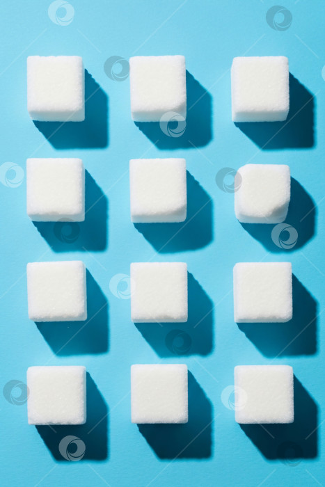 Скачать Геометрические белые кубики сахара на синем фоне, вертикальный шаблон для сладких блюд, связанных с сахарным диабетом и концепциями здорового питания, с пространством для копирования текста. фотосток Ozero