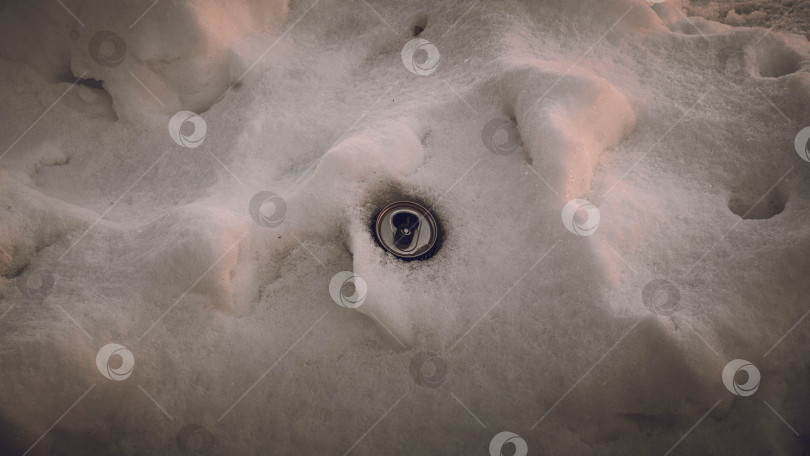 Скачать Алюминиевая пустая банка спрятана в снегу. Окружающая среда. фотосток Ozero