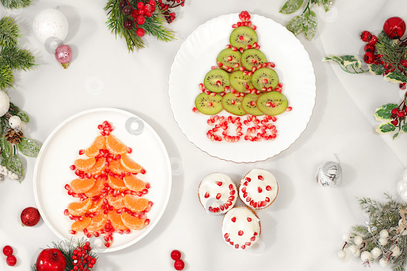 Скачать Рождественские и новогодние блюда. Творожные маффины с гранатами в глазури с цифрами 2026 и елочкой из киви и мандаринов для праздничного стола, идея для украшения блюда фотосток Ozero