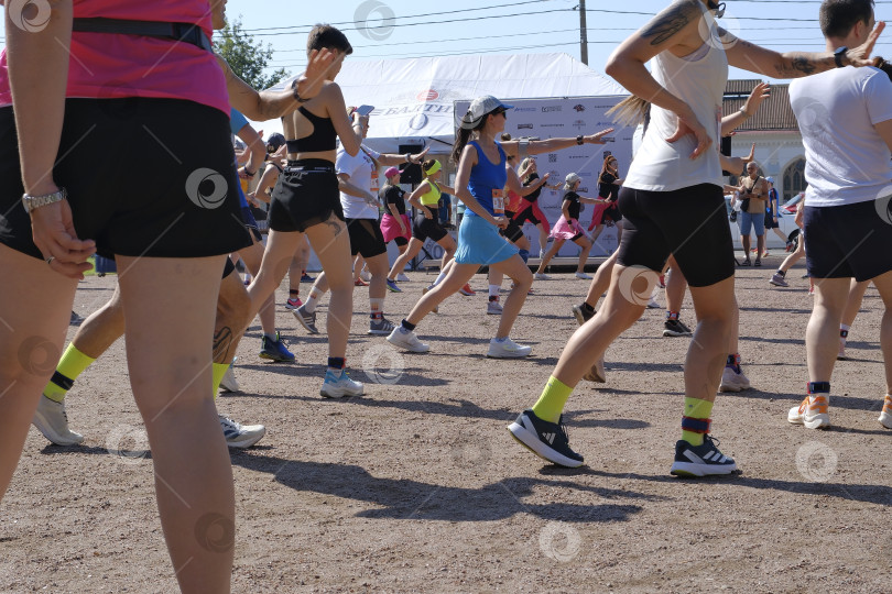 Скачать В танцевальном ритме на спортивной площадке перед забегом Разогрев мышц и поднятие настроения. фотосток Ozero