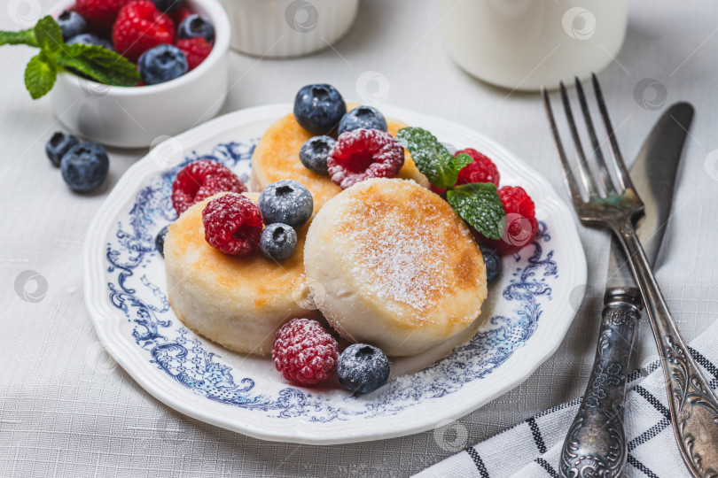 Скачать Сырники с сахарной пудрой и ягодами на тарелке фотосток Ozero
