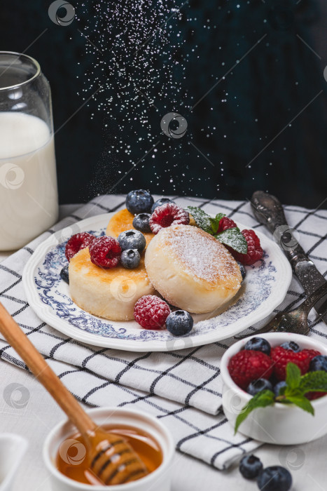 Скачать Сырники с сахарной пудрой и ягодами на тарелке фотосток Ozero