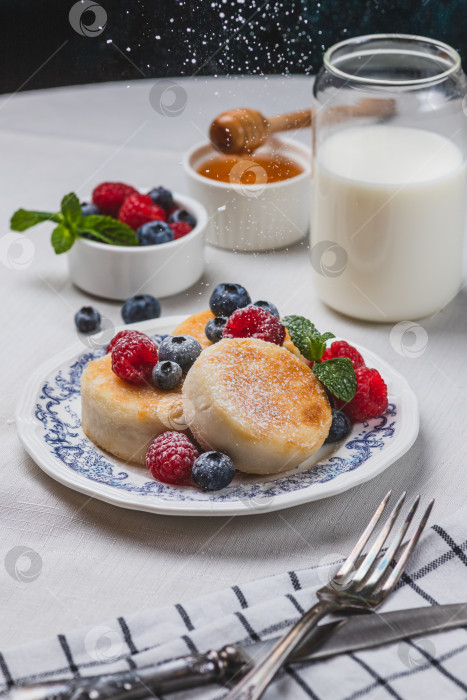 Скачать Сырники с сахарной пудрой и ягодами на тарелке фотосток Ozero