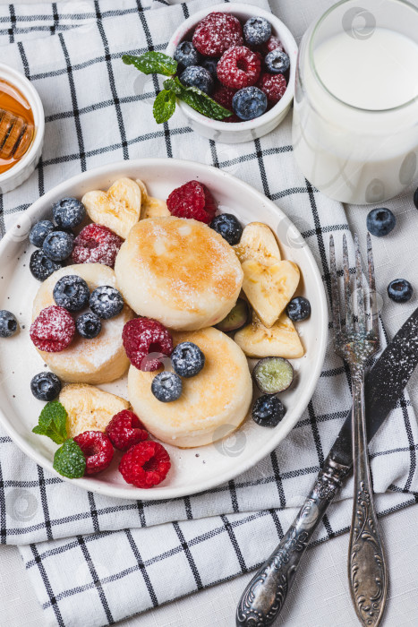 Скачать Сырники с сахарной пудрой и ягодами на тарелке фотосток Ozero