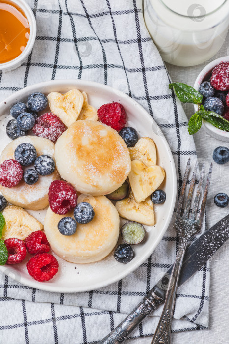 Скачать Сырники с сахарной пудрой и ягодами на тарелке фотосток Ozero