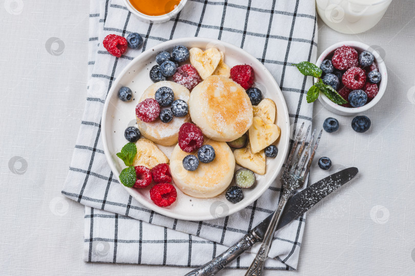 Скачать Сырники с сахарной пудрой и ягодами на тарелке фотосток Ozero