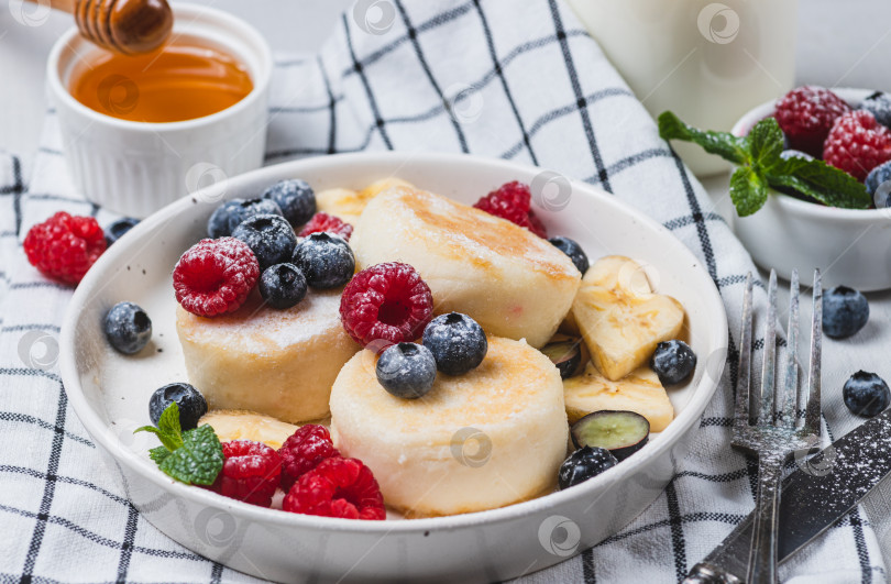 Скачать Сырники с сахарной пудрой и ягодами на тарелке фотосток Ozero
