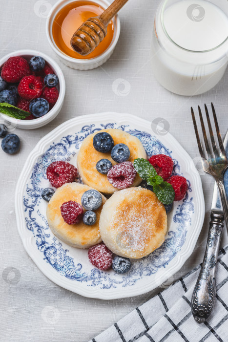 Скачать Сырники с сахарной пудрой и ягодами на тарелке фотосток Ozero