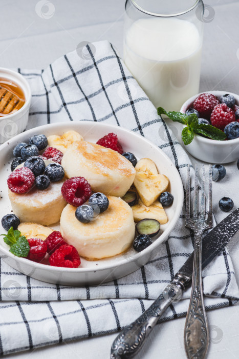 Скачать Сырники с сахарной пудрой и ягодами на тарелке фотосток Ozero