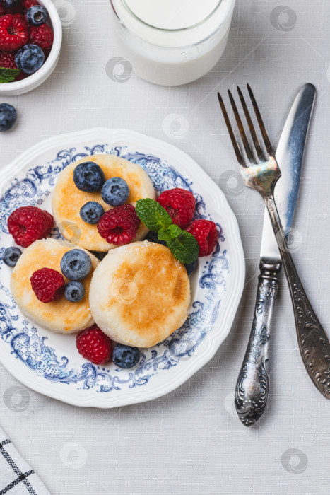 Скачать Сырники с сахарной пудрой и ягодами на тарелке фотосток Ozero