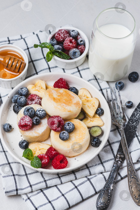 Скачать Сырники с сахарной пудрой и ягодами на тарелке фотосток Ozero