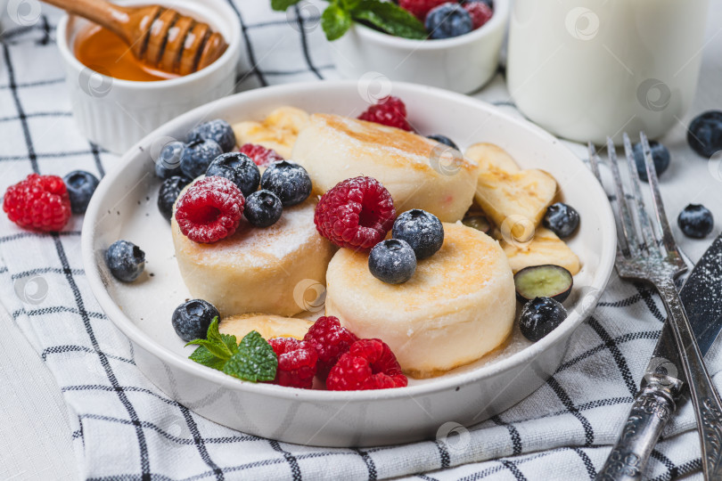 Скачать Сырники с сахарной пудрой и ягодами на тарелке фотосток Ozero