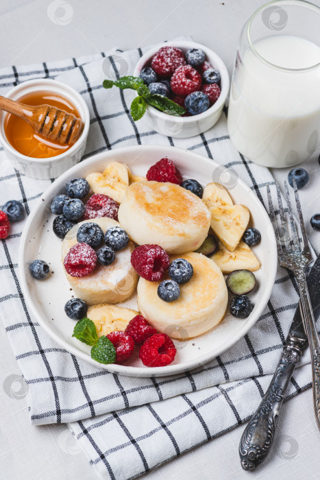 Скачать Сырники с сахарной пудрой и ягодами на тарелке фотосток Ozero