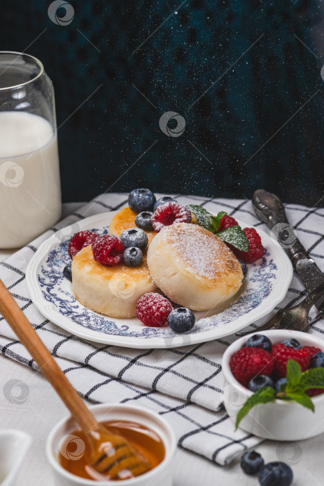 Скачать Сырники с сахарной пудрой и ягодами на тарелке фотосток Ozero
