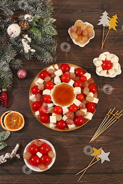 Скачать Традиционный праздничный салат с сыром фета, помидорами, виноградом, оливками и медом с еловыми ветками и украшениями, идея оформления блюда, рождественские и новогодние блюда, шаблон меню и баннер для ресторана фотосток Ozero