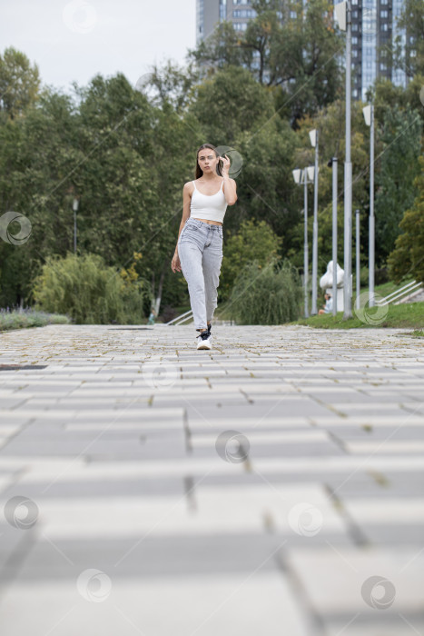 Скачать Молодая красивая брюнетка прогуливается по набережной фотосток Ozero