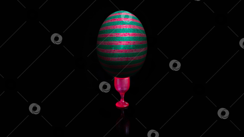 Скачать Яйцо стоит на подставке, подставка в виде бокала розового цвета. Черный фон. фотосток Ozero