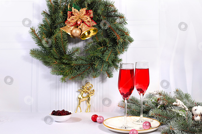 Скачать Рождественский алкогольный коктейль с красным шампанским "Мимоза" и клюквой в бокалах на праздничном фоне с еловыми ветками и украшениями, концепция бара и сочельника, алкогольные напитки на вечеринке фотосток Ozero