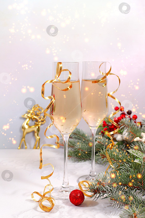 Скачать с Новым Годом. Два бокала шампанского на праздничном фоне еловых веток и украшений - концепция кануна Рождества. Рождественский и новогодний макет для дизайна и продаж продукции фотосток Ozero