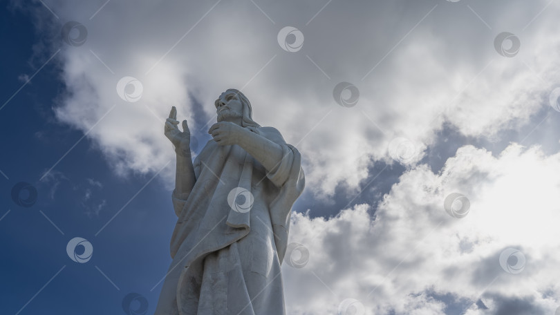 Скачать Огромная статуя Христа на фоне голубого неба и облаков. фотосток Ozero