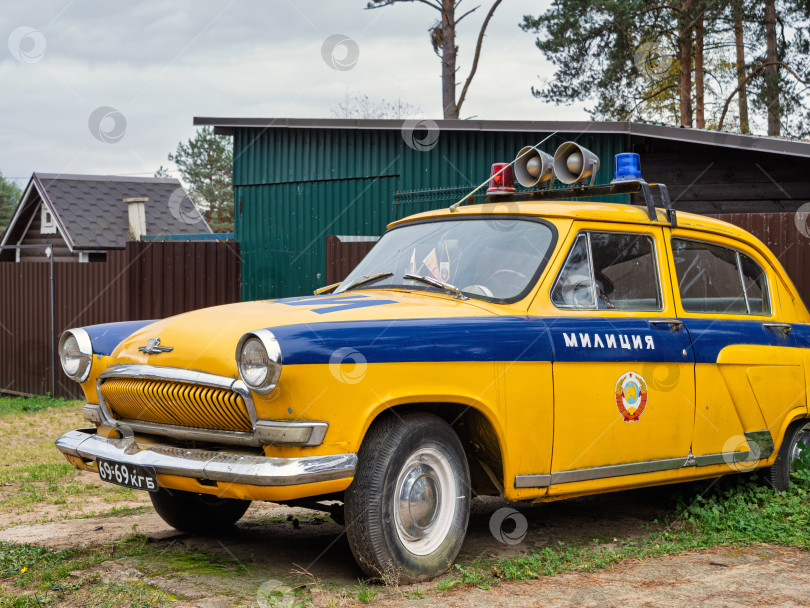 Скачать Крупный план исторического милицейского автомобиля Волга (ГАЗ-21) желто-синего цвета. Детали кузова, решетка радиатора и эмблема милиции на двери. фотосток Ozero