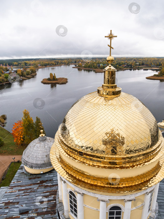 Скачать Величественный панорамный вид с колокольни Нило-Столбенского монастыря на озеро Селигер. Блестящий золотой купол на переднем плане, два островка и изрезанный берег, окруженный живописными осенними деревьями, передают созерцательное настроение. фотосток Ozero