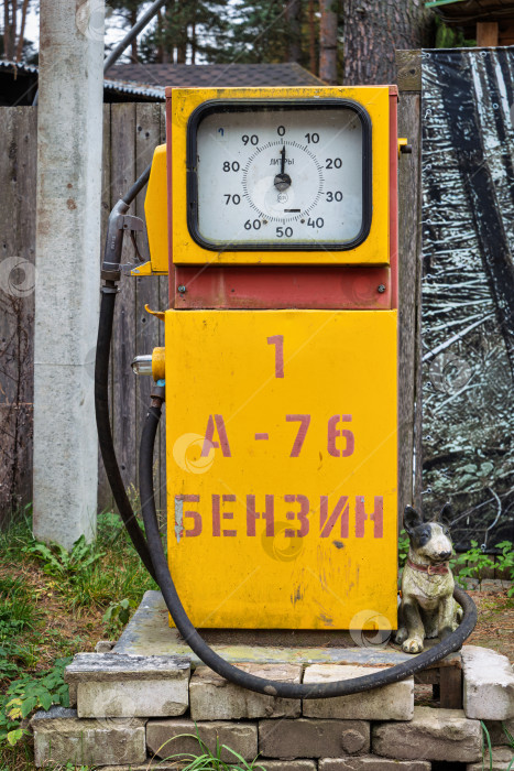 Скачать Крупный вертикальный план старой желтой бензоколонки советской эпохи с надписью А-76 БЕНЗИН. Ретро-объект с циферблатом и заправочным пистолетом. фотосток Ozero