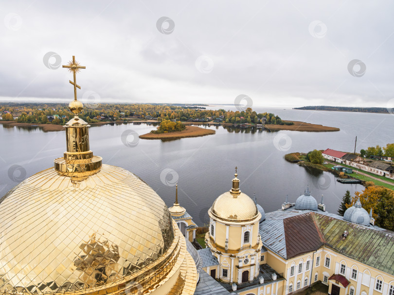 Скачать Панорамный вид с колокольни Нило-Столбенского монастыря на озеро Селигер. Яркие золотые купола на переднем плане, изрезанный берег, островок и живописные осенние деревья передают умиротворение. фотосток Ozero