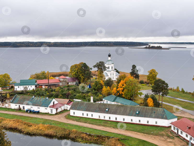 Скачать Панорамный вид с колокольни Нило-Столбенского монастыря на озеро Селигер. Белая Крестовоздвиженская церковь, длинные хозяйственные постройки и безмятежная гладь озера с островком передают умиротворение. фотосток Ozero