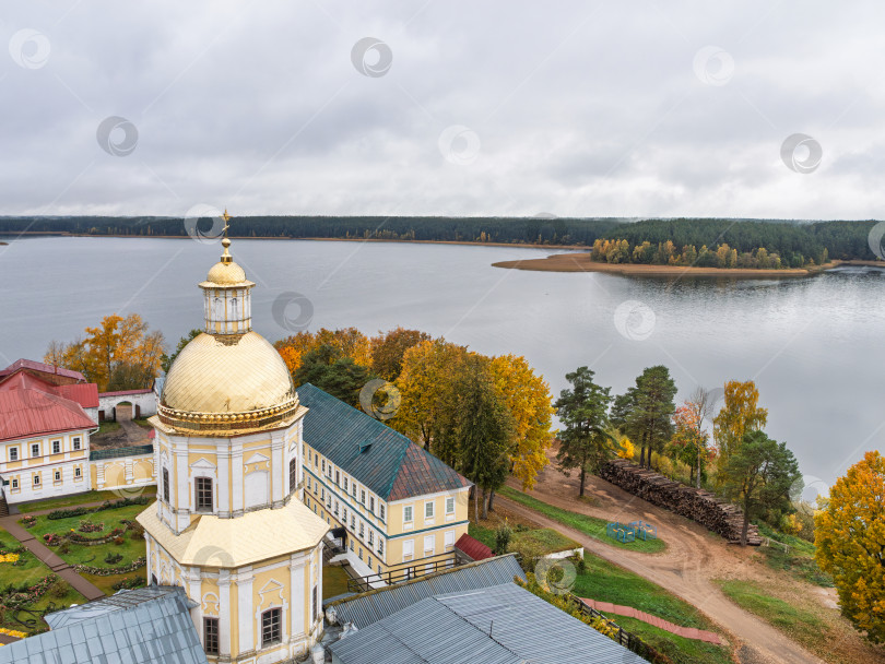 Скачать Панорамный вид с колокольни Нило-Столбенского монастыря на озеро Селигер. Золотой купол Петропавловской церкви, монастырские корпуса, склад бревен и изрезанный берег, окруженный живописными осенними деревьями, передают созерцательное настроение. фотосток Ozero