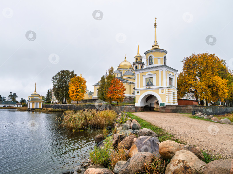 Скачать Вход в Нило-Столбенский монастырь (Нилова пустынь) с насыпной дороги. Каменные валуны на берегу озера Селигер и золотая осень. фотосток Ozero