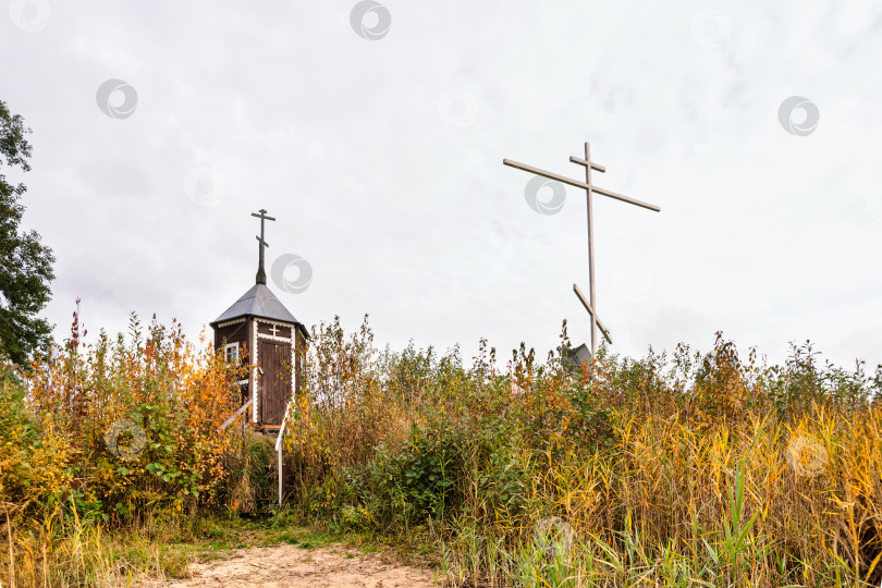 Скачать Крест и часовня на островке напротив деревни Неприе. Осенний пейзаж на озере Селигер, снятый с низкой точки. фотосток Ozero