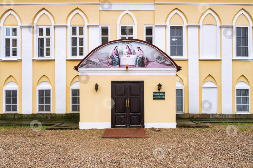 Скачать Парадный вход в монастырскую гостиницу Нило-Столбенского монастыря. Светлый фасад в стиле классицизма, арочные окна и фреска с библейским сюжетом фотосток Ozero