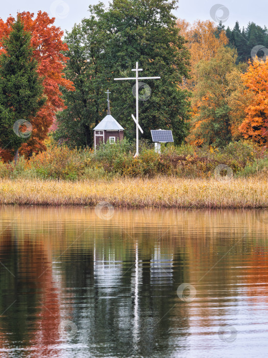 Скачать Живописный осенний пейзаж с православным крестом и часовней, построенной в память об утонувших на островке озера Селигер напротив деревни Неприе. фотосток Ozero