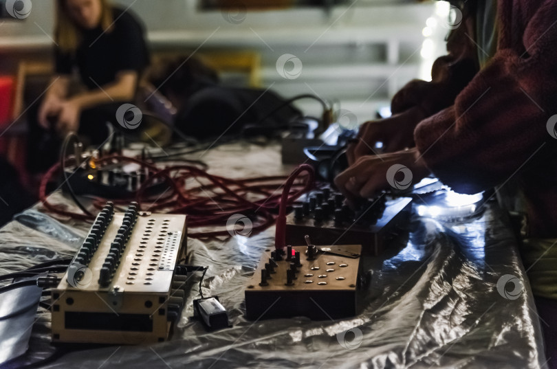 Скачать Создание экспериментального звука: Крупный план рук, настраивающих аналоговые синтезаторы и драм-машины в студии или на живом выступлении фотосток Ozero