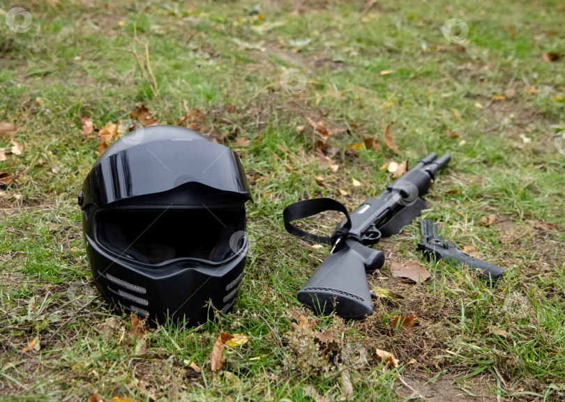 Скачать Черный мотоциклетный шлем, дробовик и пистолет лежат на траве фотосток Ozero