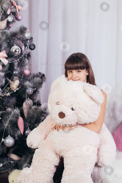 Скачать девочка с игрушечным медведем сидит на фоне рождественской елки фотосток Ozero